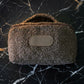 Brown textured pouch with a beige label on a black marble background
