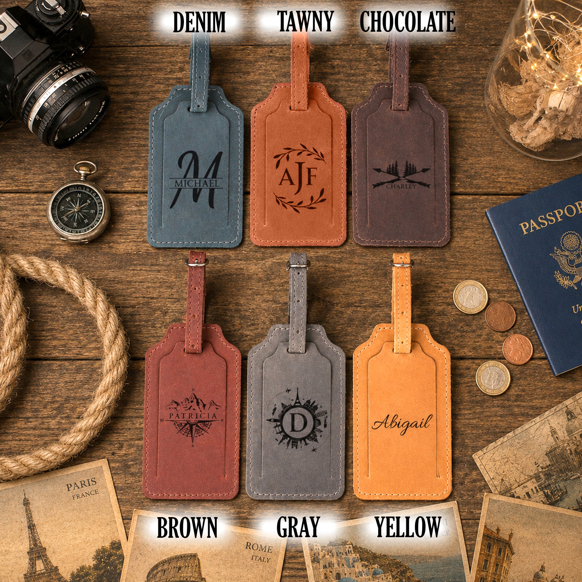 Six personalized leather luggage tags in blue, tan, brown, red, gray, and yellow, arranged on a rustic wooden background with travel-themed props. Text labels above and below indicate the available colors: DENIM, TAWNY, CHOCOLATE, BROWN, GRAY, and YELLOW.