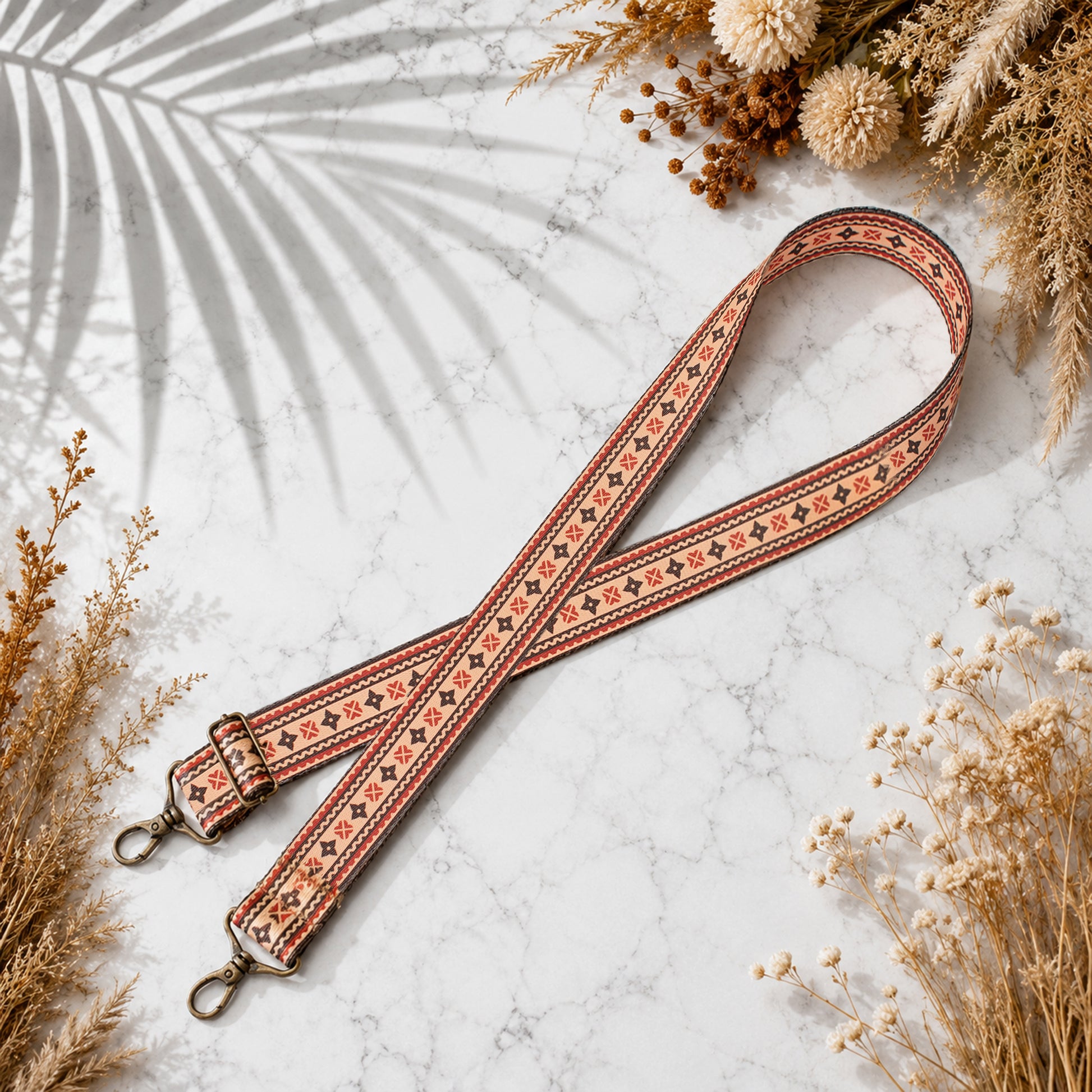 Decorative strap with floral patterns on a marble surface with dried flowers.