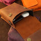 Brown leather pouch with gold rivets on a wooden surface