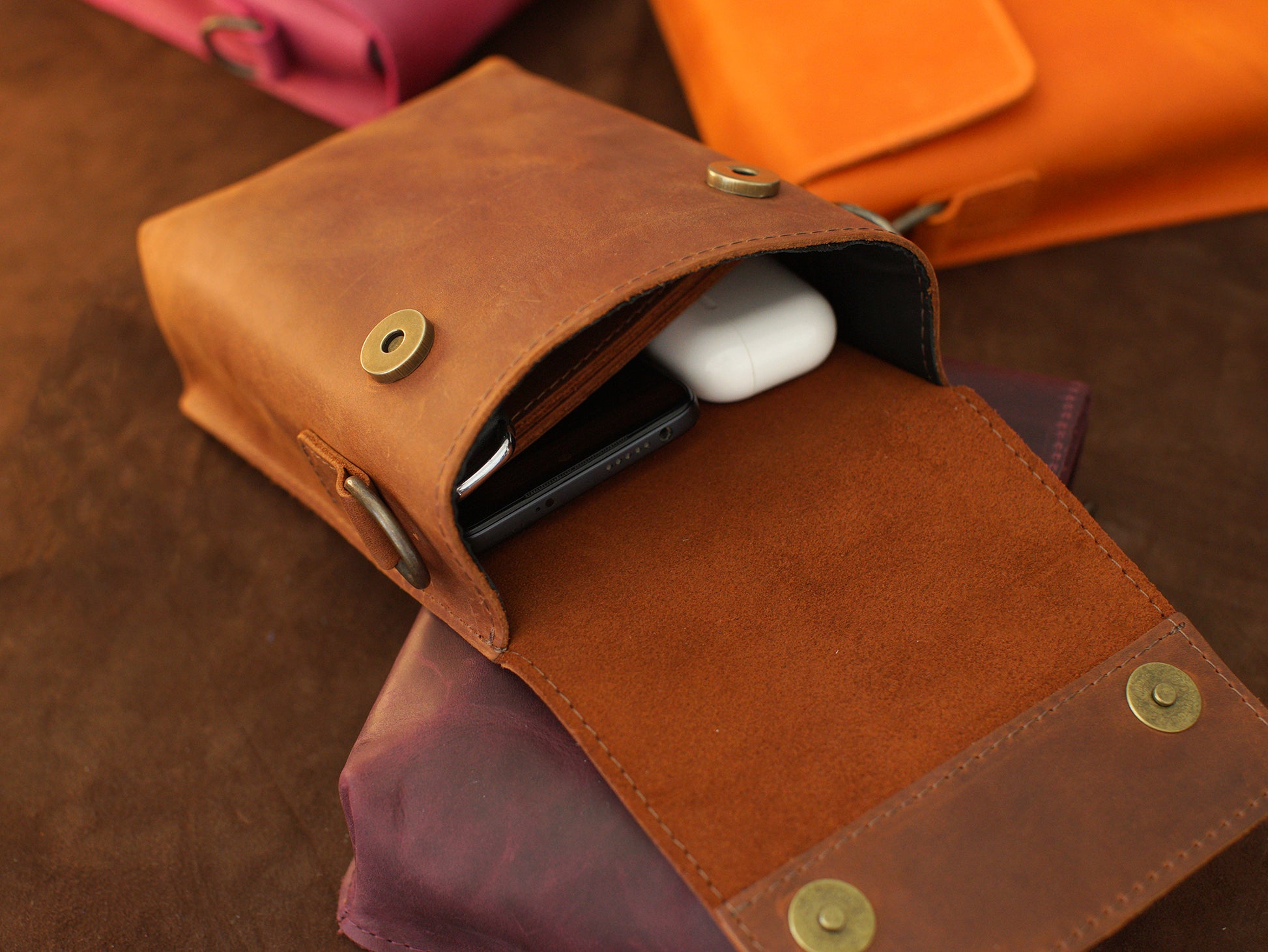Brown leather pouch with gold rivets on a wooden surface