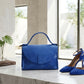 Blue handbag and high heels on a marble surface with a neutral background