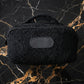 Black textured pouch on a marble surface