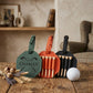 Three personalized golf tees in leather cases on a rustic wooden table, with a white golf ball, dried wheat, and lavender sprigs. The cases are sage green, terracotta orange, and black, with the name 'CHARLEY' engraved on the green case.