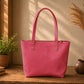 Pink tote bag on a wooden surface with decorative plants and vases in the background