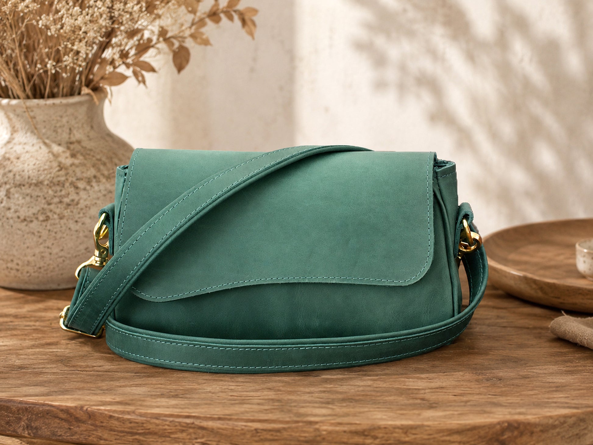 Green handbag on a wooden surface with a blurred background