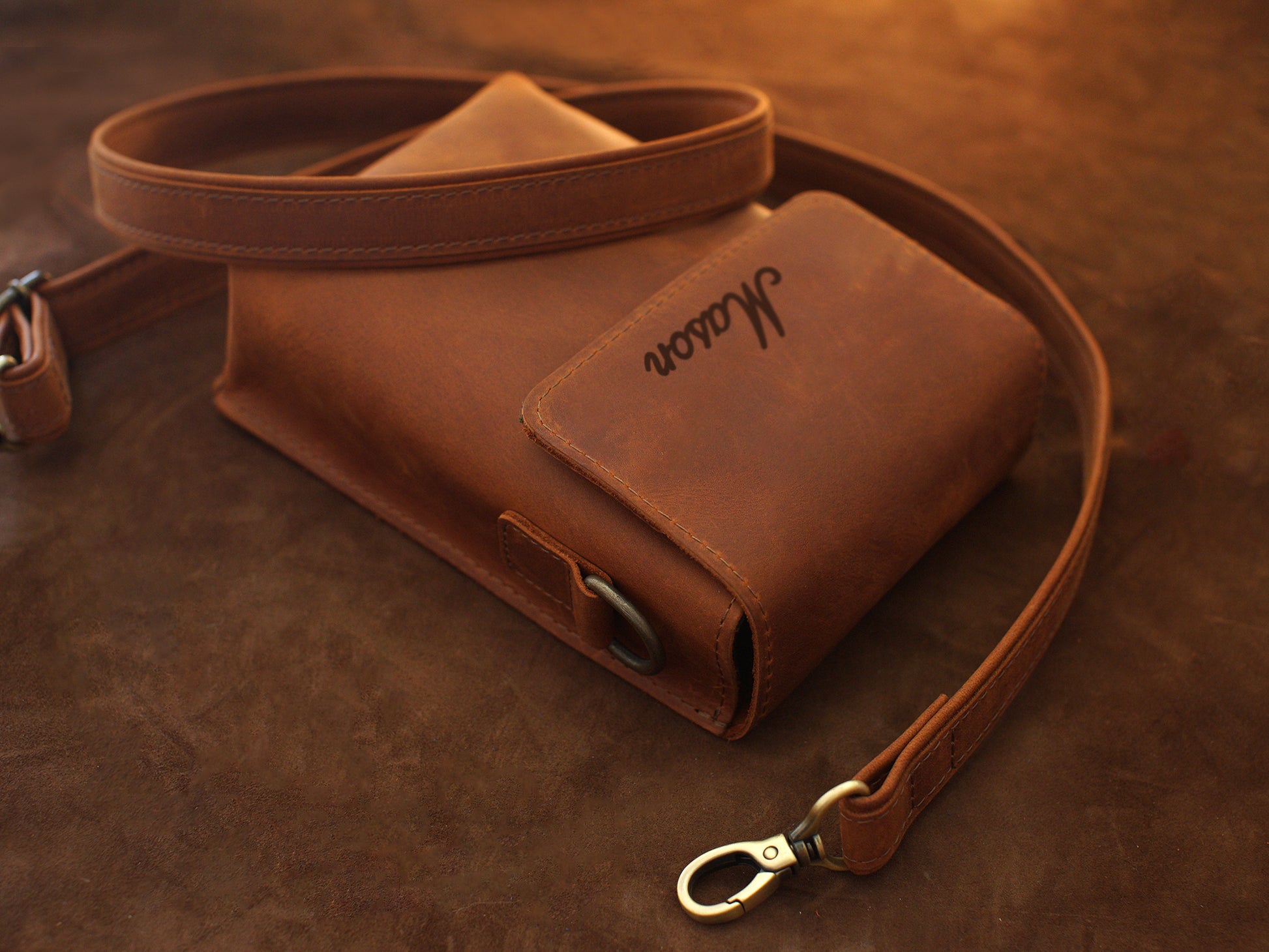Brown leather bag with strap on a brown background