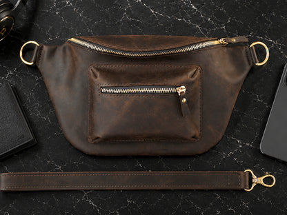 Brown leather waist bag with gold zipper on a dark surface
