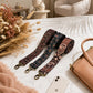 Three patterned straps on a marble surface with a phone and handbag.
