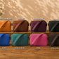 Row of colorful crossbody bags on a wooden surface with labels indicating colors.