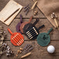 A set of six golf-themed leather luggage tags arranged on a rustic wooden tabletop with decorative props including a golf scorecard, pencil, dried lavender, wheat, burlap fabric, and a golf ball. The tags are in orange, purple, brown, black, and green, with some featuring wooden pegs or a golf hole graphic.