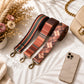 Plaid patterned strap with metal clasps on a light surface with a phone and handbag.