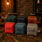 Set of personalized leather pouches in various colors with names engraved on them, against a rustic background.