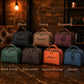 Collection of leather bags in various colors with names engraved on them, set against a rustic background.