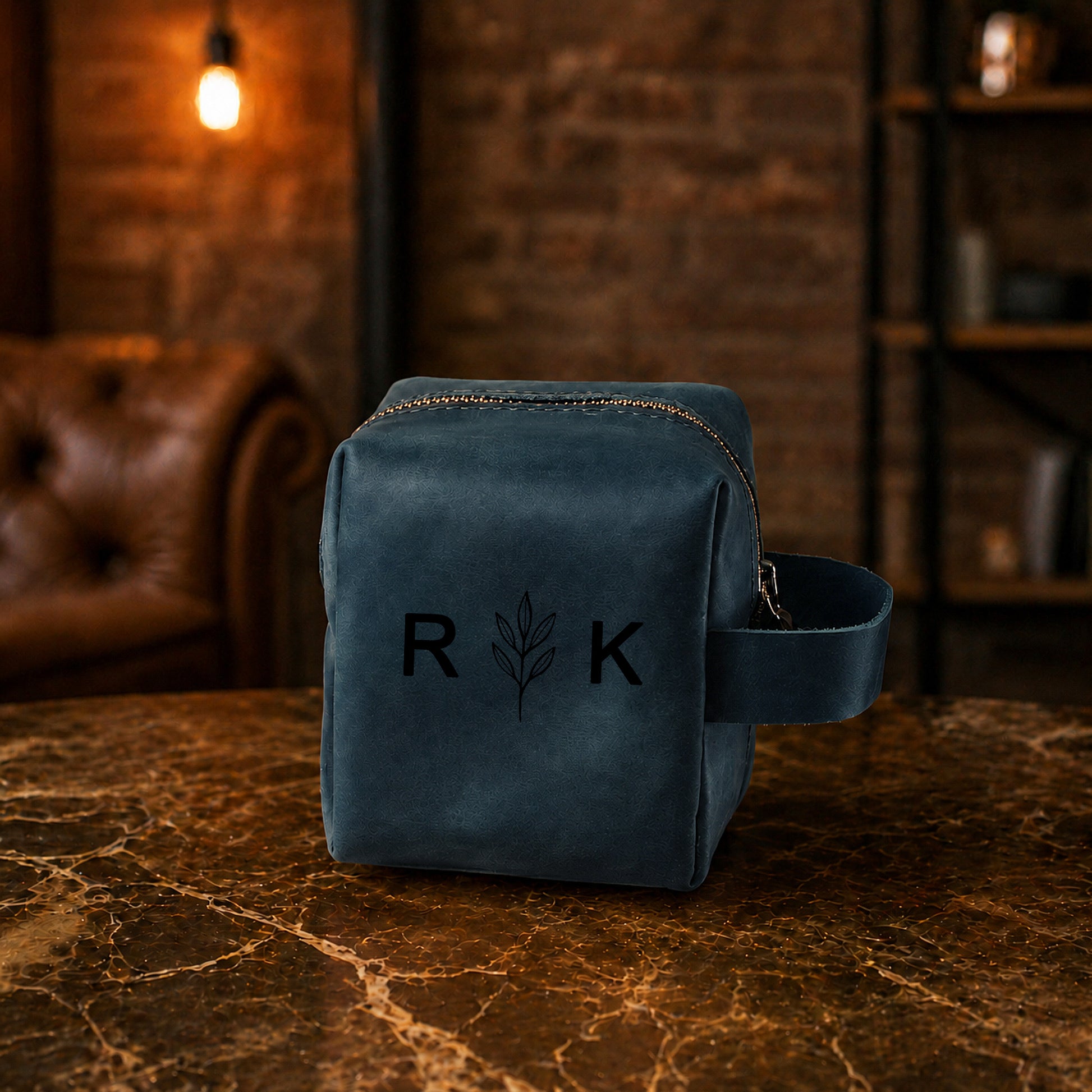 Blue leather pouch with 'R K' logo on a marble surface with a warm-toned background