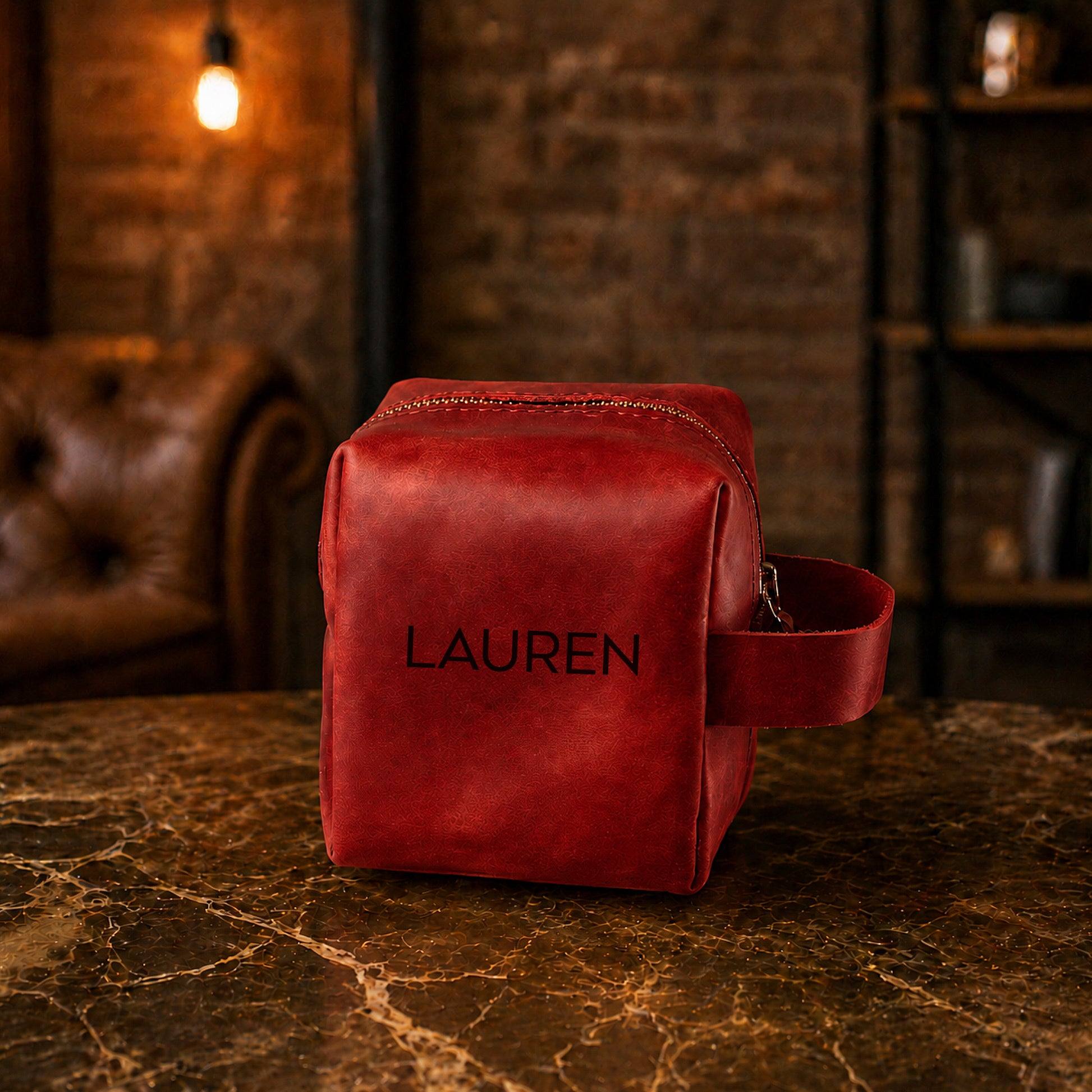Red leather bag with 'LAUREN' monogram on a marble surface with a rustic background