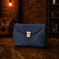 Blue handbag with 'Marshall' branding on a wooden surface with a warm-toned background.