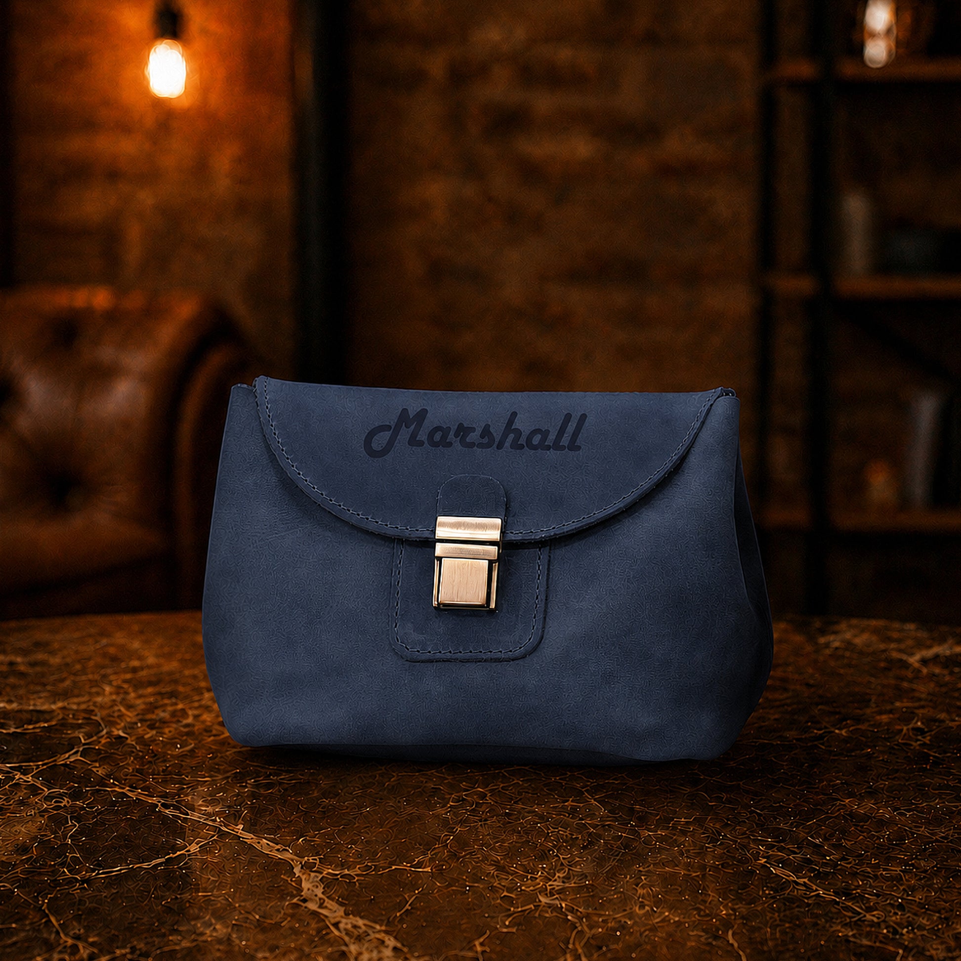 Blue handbag with 'Marshall' branding on a wooden surface with a warm-toned background.