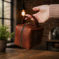Brown leather bag with 'Veronica' branding held by a hand in a warm-toned indoor setting.