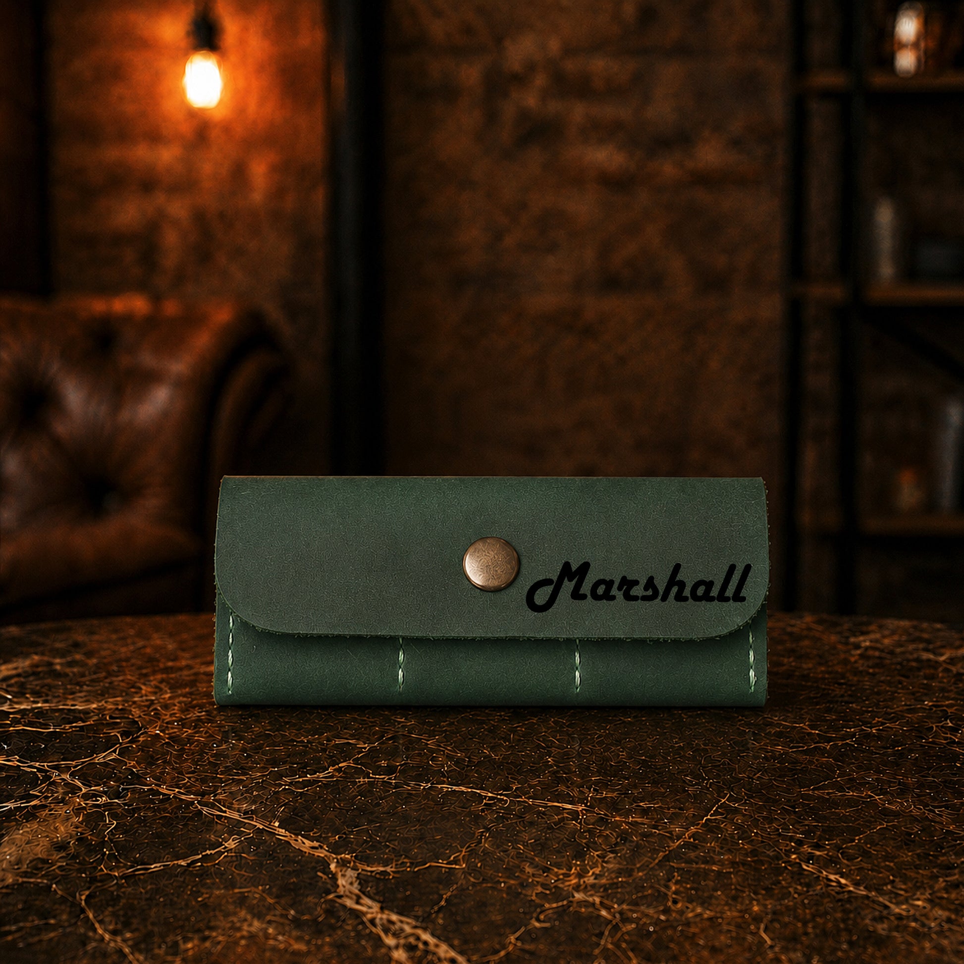 Green leather wallet with 'Marshall' branding on a marble surface with a dark background.