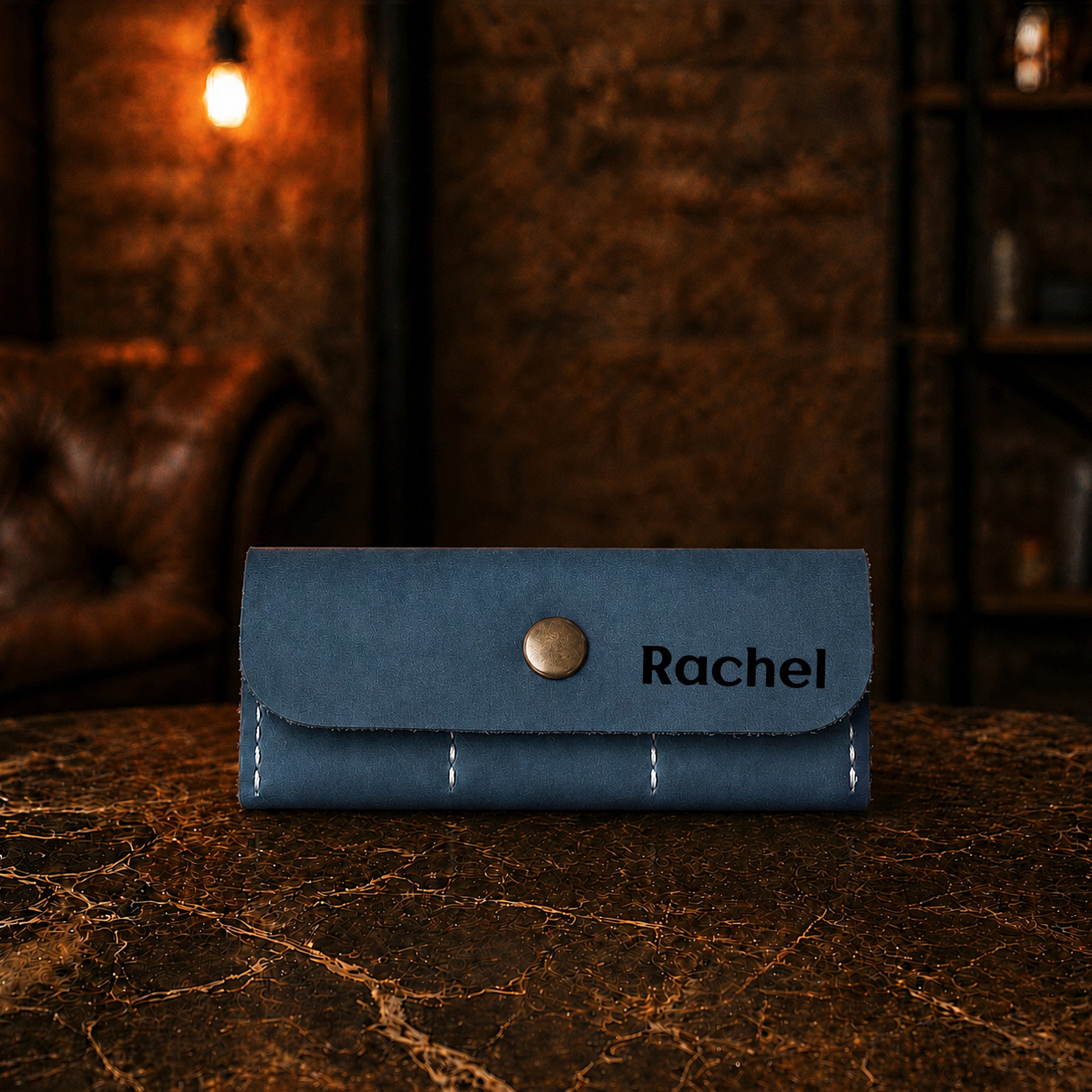 Blue wallet with 'Rachel' engraving on a dark surface with a blurred background