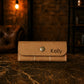 Brown leather wallet with 'Kelly' engraving on a dark surface
