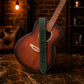 Acoustic guitar with a strap on a wooden surface against a brick wall background