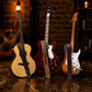 Three guitars with branded straps on a dark surface against a brick wall.