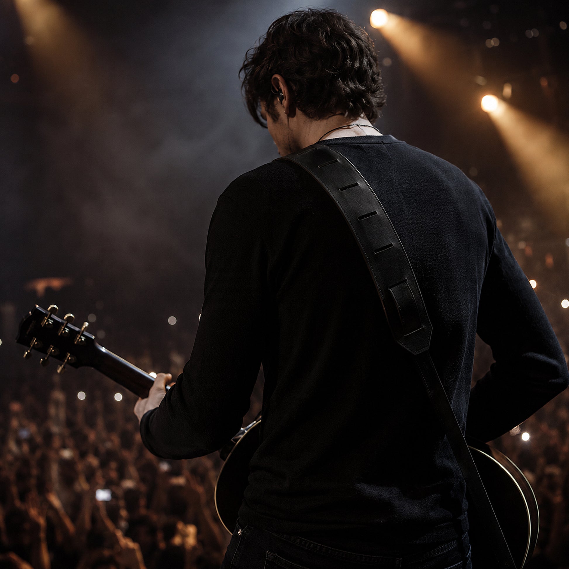 Person playing guitar on stage with lights and audience in the background