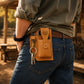 Person wearing a brown leather pouch with keys on a wooden background