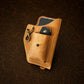 Brown leather pouch with phone and key on a dark brown background