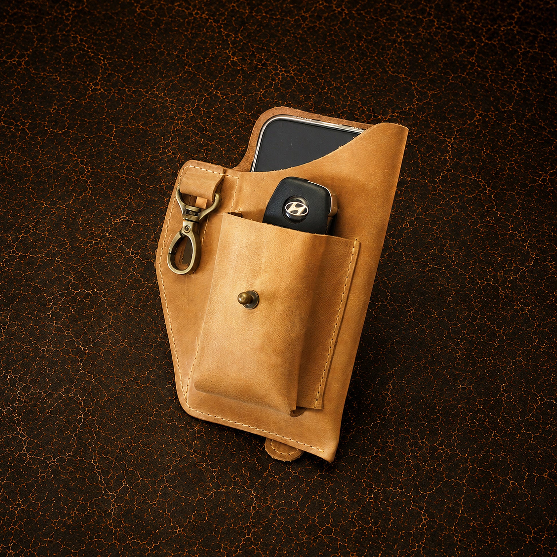 Brown leather pouch with phone and key on a dark brown background