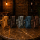 Five leather pouches in various colors arranged on a textured surface with a warm-toned background.