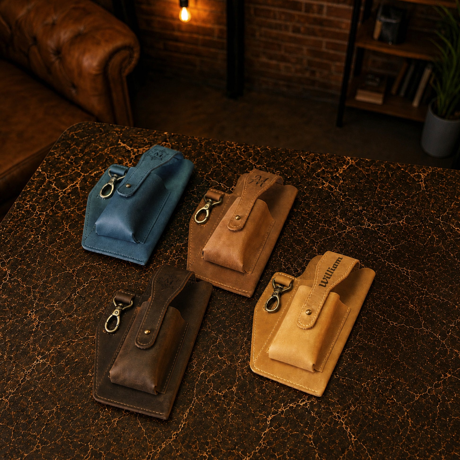 Four leather pouches in blue, brown, and beige on a textured surface with a warm-toned background.