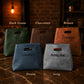 Five leather bags in different colors with names engraved on them, set against a rustic brick wall background.