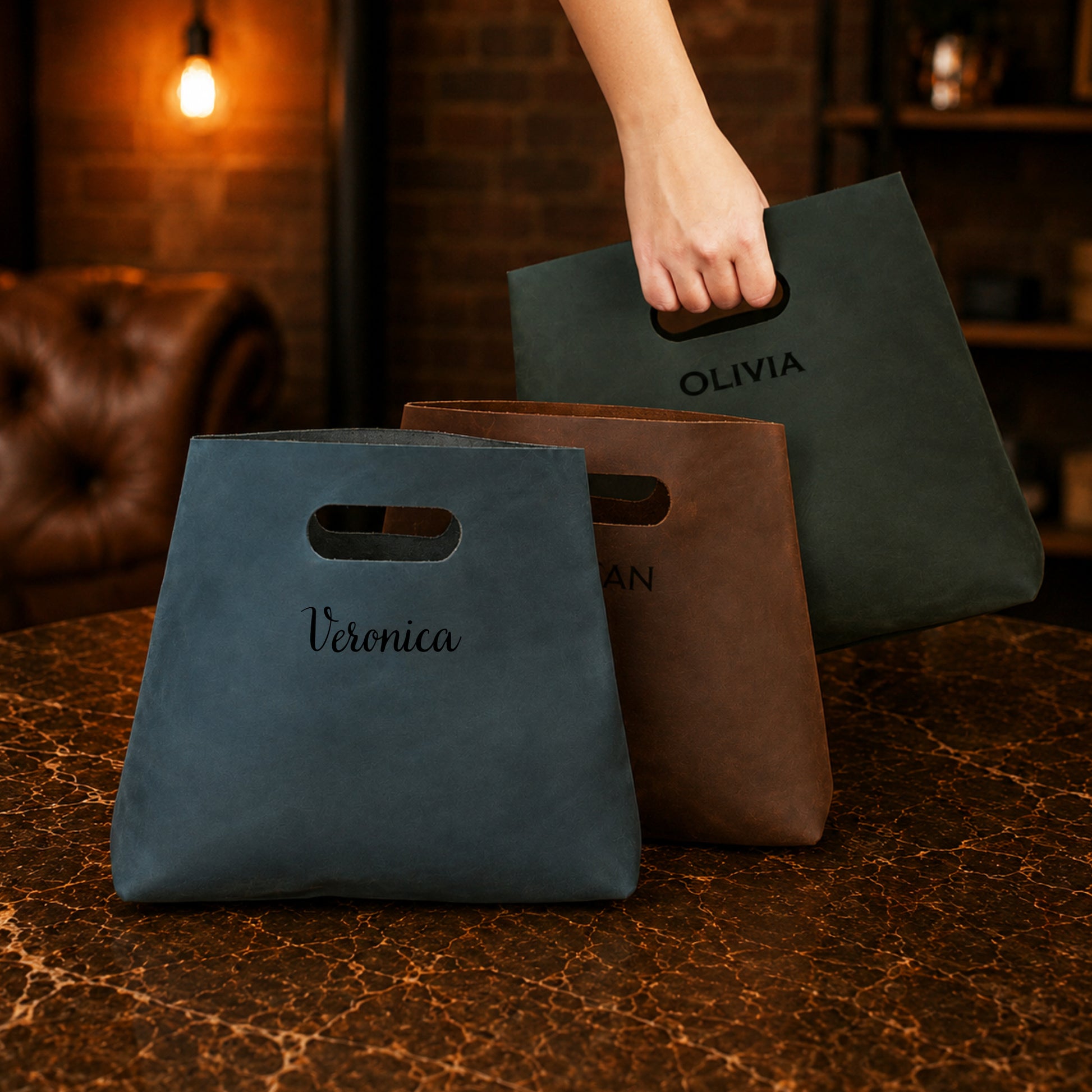Three bags with names 'Veronica', 'Olivia', and 'Natalie' on a textured surface.