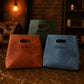 Three bags with names embossed on them, placed on a textured surface with a warm-toned background.