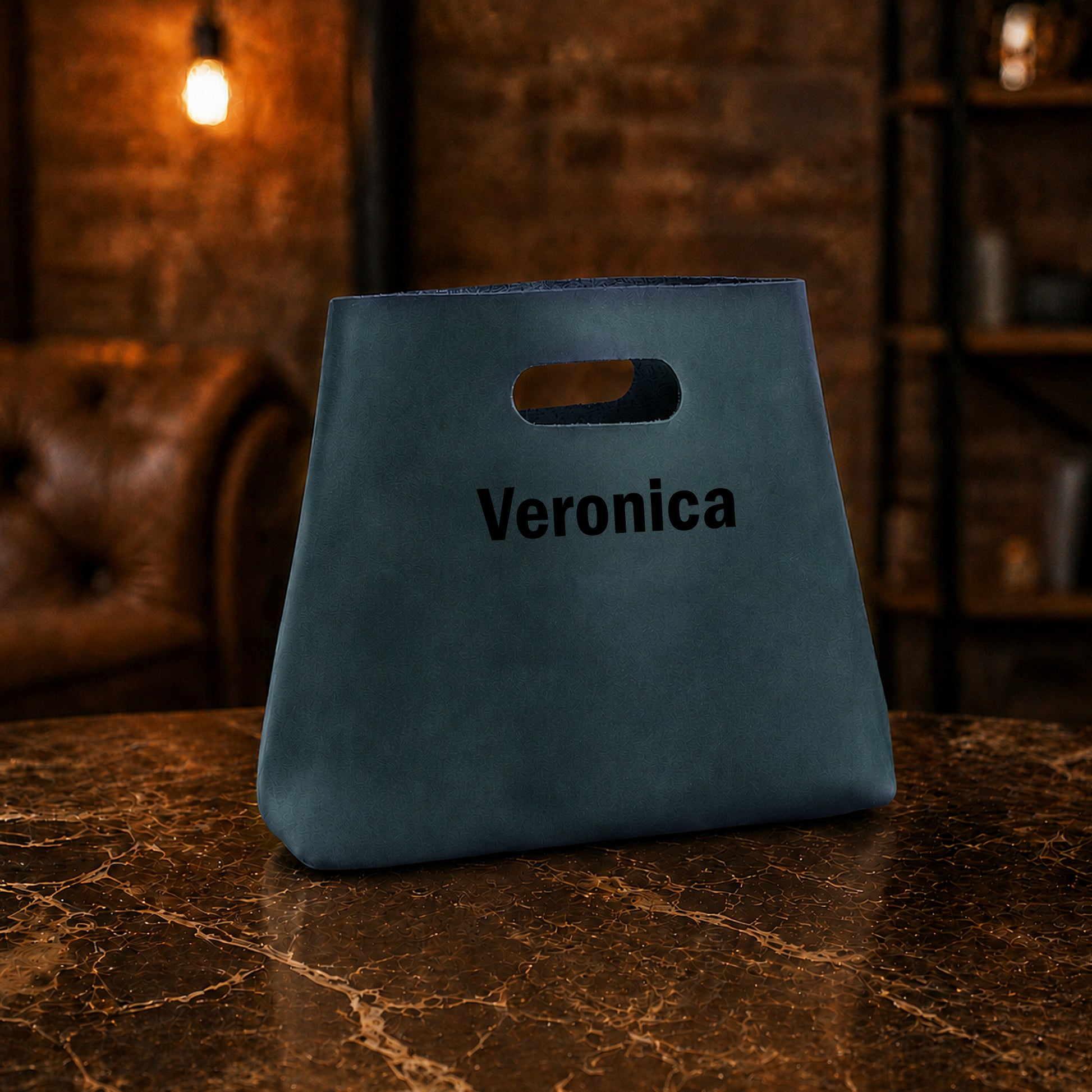 Blue bag with 'Veronica' printed on it on a marble surface with a dark background