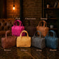 Six small top-handle satchel bags in different colors are arranged on a dark marble surface in a rustic indoor setting. Text labels above and below identify the colors: Pink, Chocolate, Tawny, Brown, Yellow, Gray, and Denim.