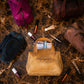 Brown handbag with 'Margaret' embroidery surrounded by makeup items on a marble surface