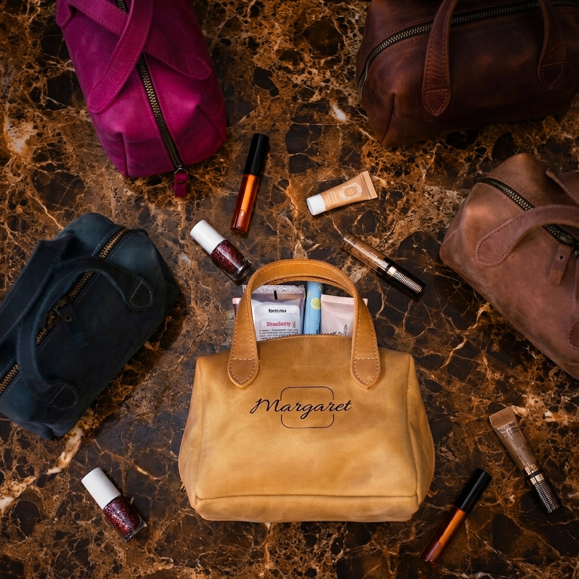 Brown handbag with 'Margaret' embroidery surrounded by makeup items on a marble surface