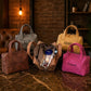 Collection of handbags in various colors with visible branding on a textured surface.