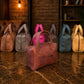 Collection of leather handbags in various colors on a textured surface with a warm light.