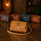 Collection of leather bags with monograms on a wooden surface.