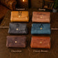 Collection of leather pouches in various colors with personalized names on a textured surface.