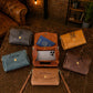 Collection of leather handbags with monogram initials on a textured surface.