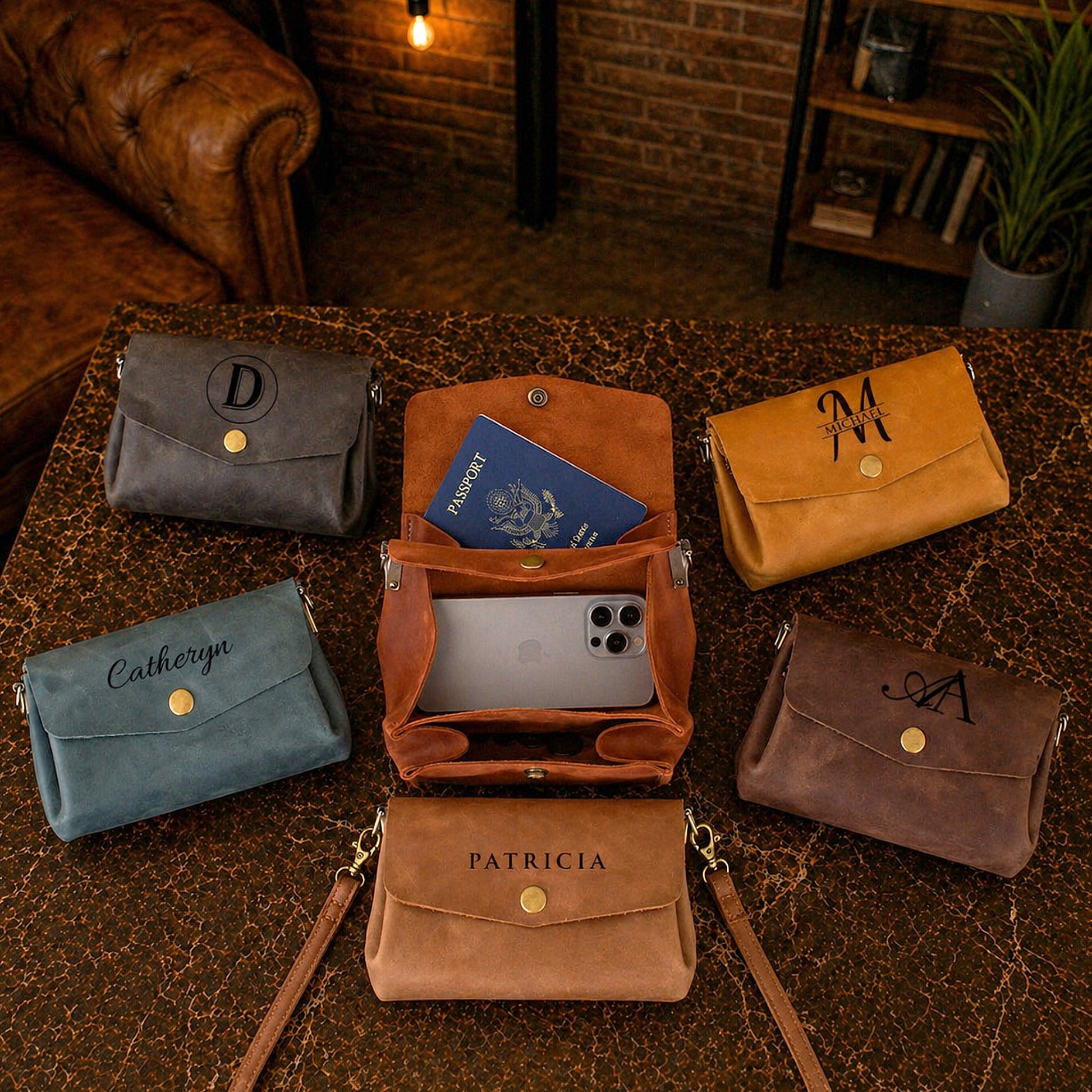 Collection of leather handbags with monogram initials on a textured surface.