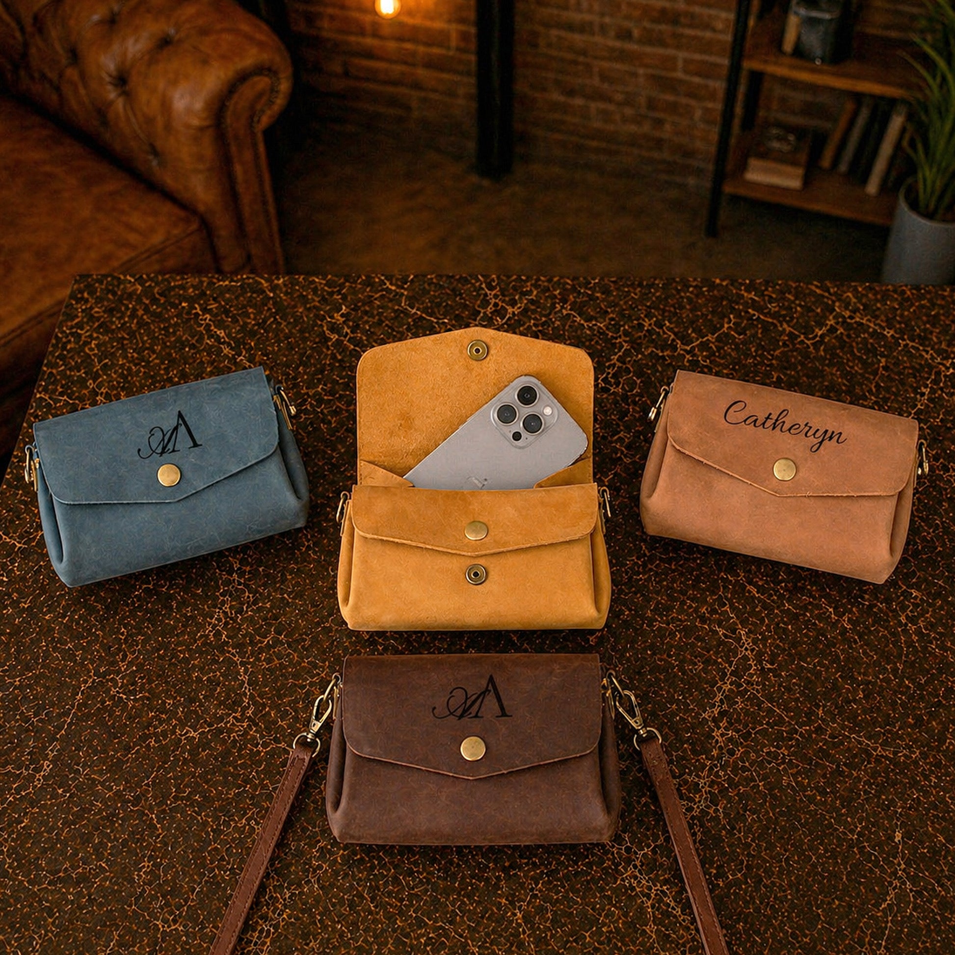 Four suede handbags in blue, orange, and brown on a textured surface with a warm-toned background.